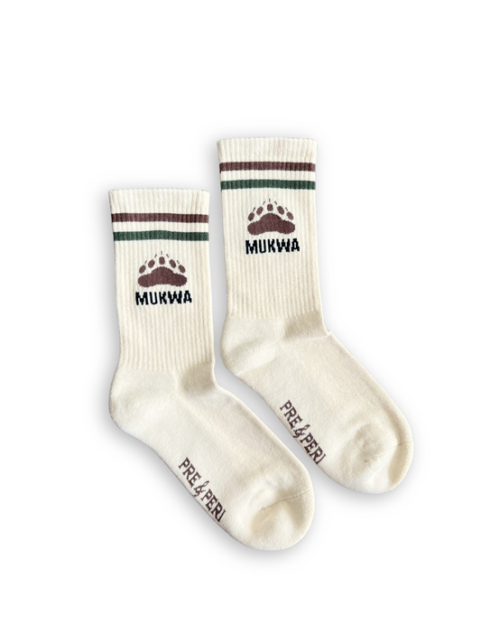 Pair of cream-colored socks with brown and green accents and 'Mukwa' under a bear paw print
