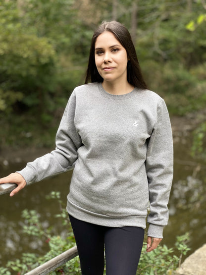 Heather grey crewneck sweatshirt on a woman with small white stylized ampersand on left chest